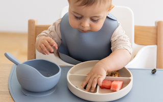 Baby eating watermelon with mess-free silicone placemat and divided plate, easy clean food catcher for mealtime