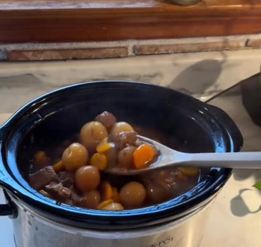 Crock-Pot slow cooker with hearty stew, carrots, and potatoes on kitchen counter