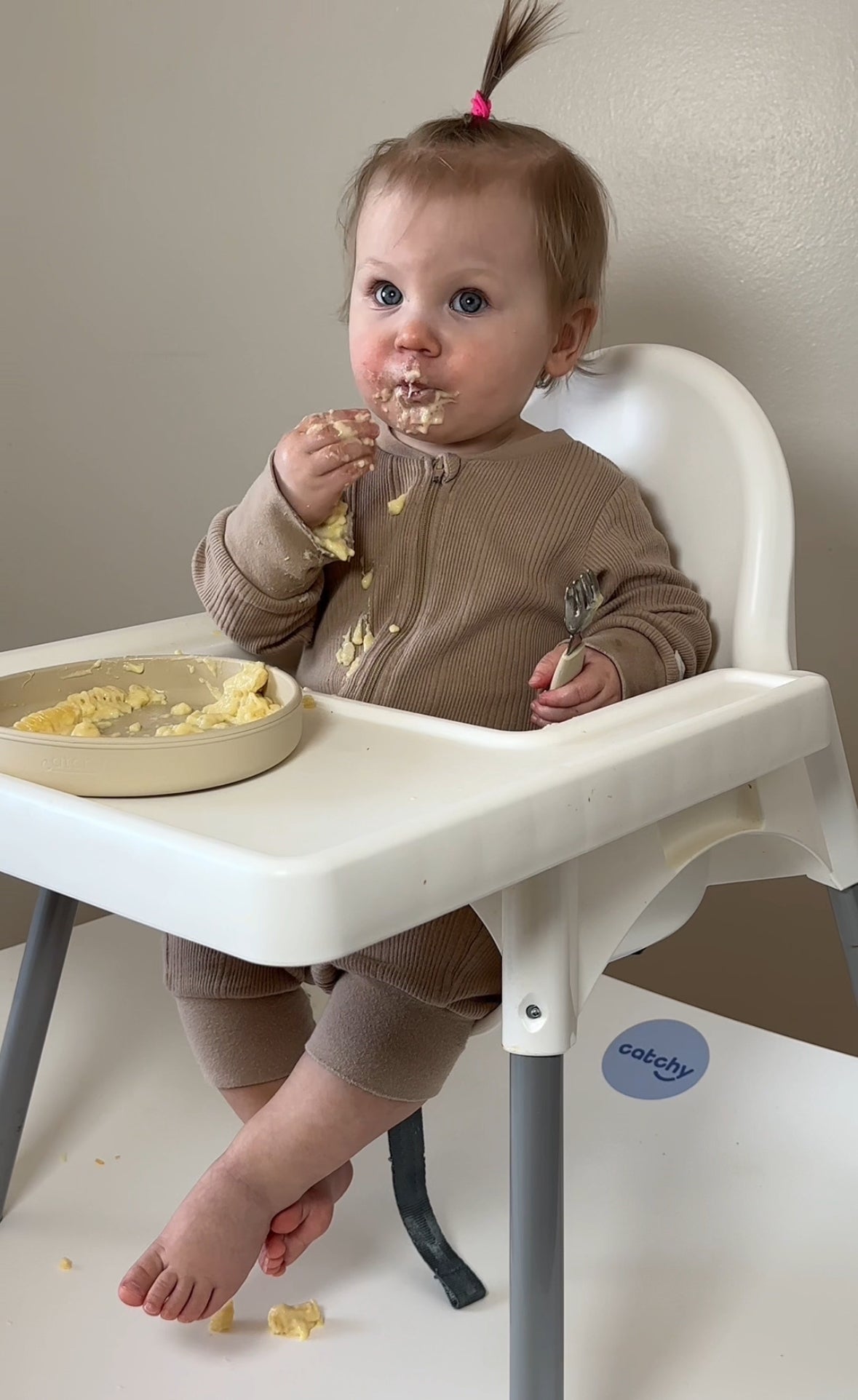 Baby eating messy meal in high chair with Catchy floor mat protecting flooring from food spills