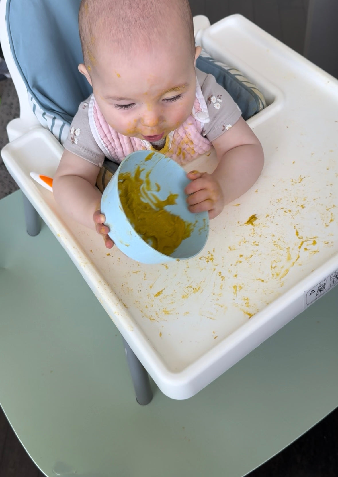 Baby eating messy puree in high chair with food-safe catch mat, easy wipe clean, protects floors