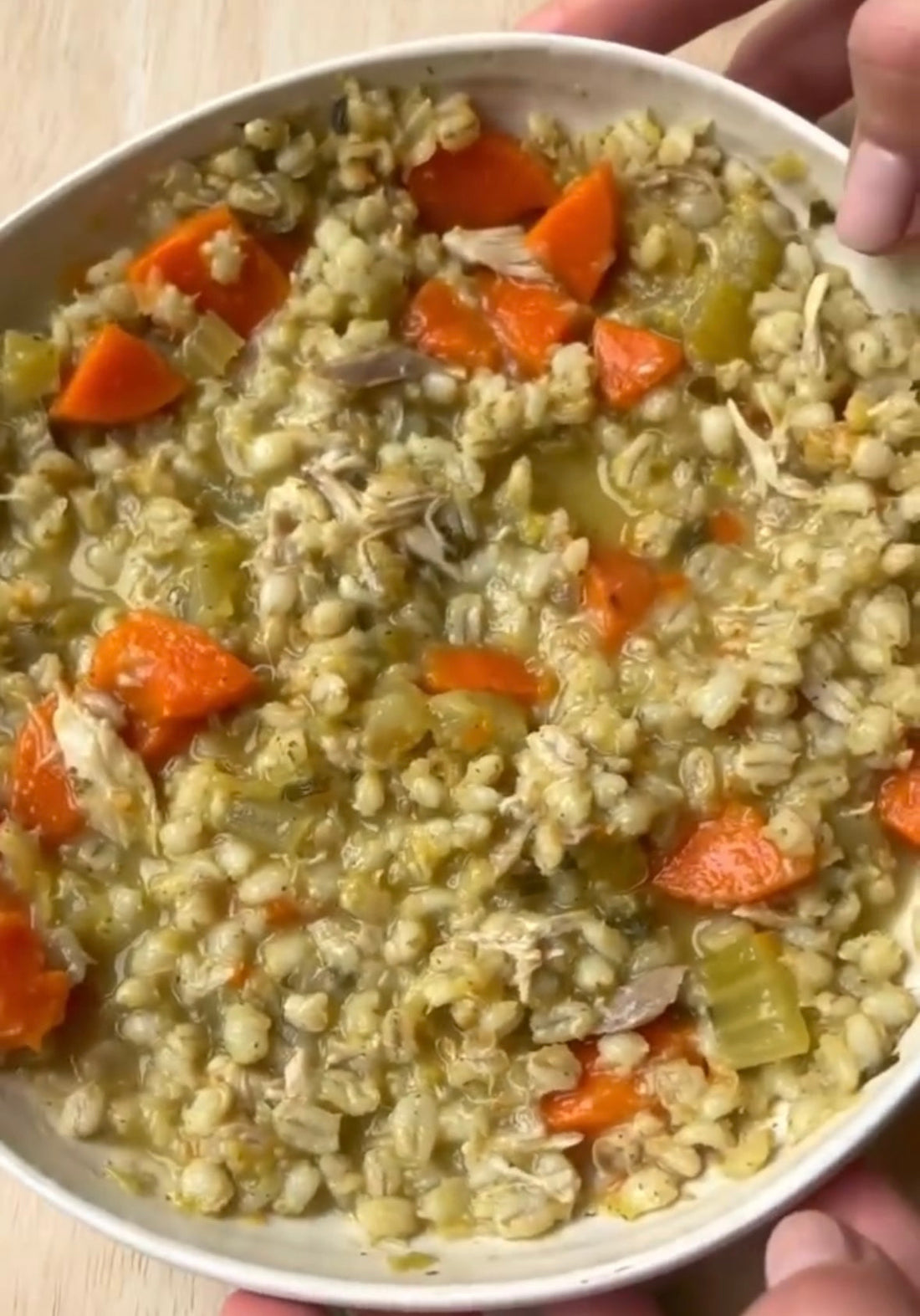 Hearty chicken barley soup with carrots and celery in a white bowl, perfect for mess-free meals.